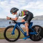 male bike riding in front of a lake wearing Rudy Project NA gear