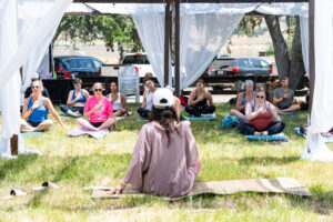 Yoga teacher sitting in front of Wildflower attendees.