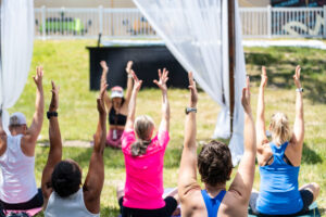 Wildflower yoga class attendees with their hands up.